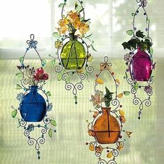 three colorful glass vases hanging from a window sill with flowers in them and vines on the sides