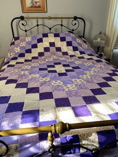 a bed with a purple and white quilt on it