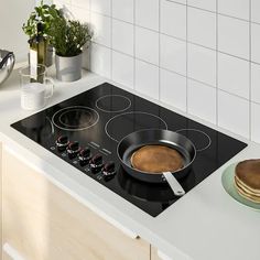 a stove top with a pan on the burner and some pancakes next to it