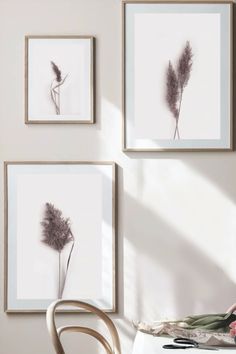 three framed pictures hang on the wall next to a table with a vase and flowers