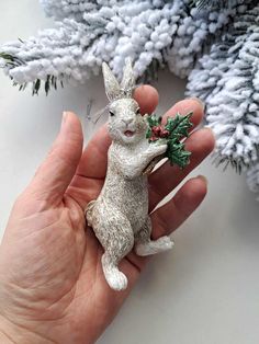 a hand holding a small white rabbit ornament