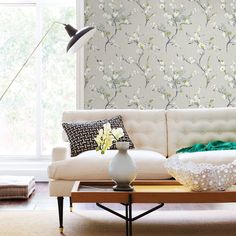 a living room with a couch, table and flower wallpapers on the walls