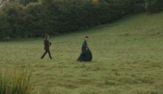 two people walking across a lush green field