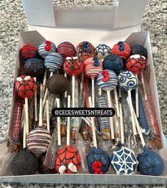 a box filled with cake pops covered in spiderman designs