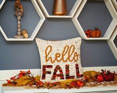 a decorative pillow that says hello fall on it in front of hexagonal shelves