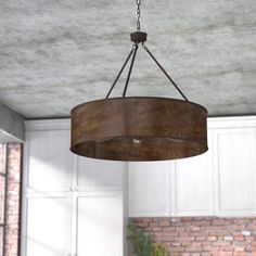 a light fixture hanging from the ceiling in a room with white cabinets and brick walls