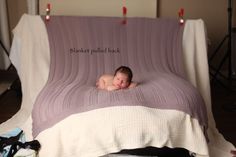 a baby is sleeping on a blanket in the middle of a bed with lights hanging above it