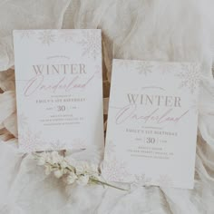 two wedding cards sitting next to each other on top of a white cloth covered bed