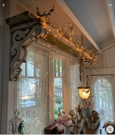 a window with lights hanging from it's side and some flowers in the middle