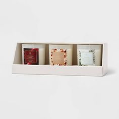 three candles in a white box on a white background, one is filled with different types of items