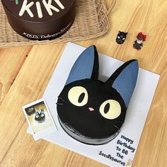 a black cat cake sitting on top of a wooden table