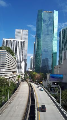 an empty highway in the middle of a city with tall buildings and skyscrapers behind it