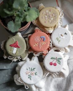 several embroidered objects sitting on top of a table next to a potted plant