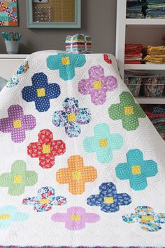 a bed with a quilt on top of it next to a book shelf filled with books