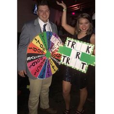 a man and woman holding up a wheel of fortune sign