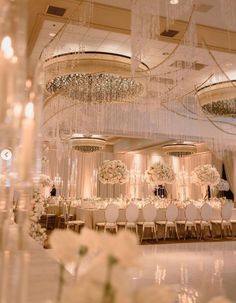 a room filled with lots of white flowers and chandeliers