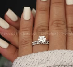 a woman's hand with white manicured nails and a diamond ring on it