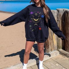 a woman standing on top of a wooden pier next to the ocean with her arms outstretched