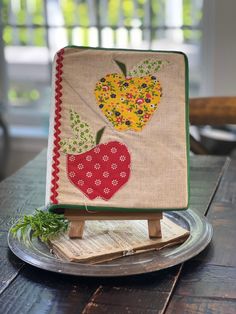 an apple and strawberry appliqued on a small wooden easel sitting on top of a table