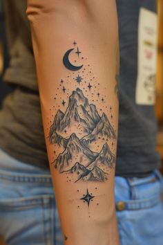 a person with a mountain and stars tattoo on their arm