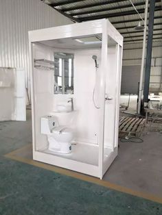 a white toilet sitting inside of a room next to a shower and sink in a warehouse