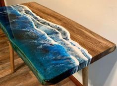 a wooden table topped with a blue and white wave painted on top of it's surface