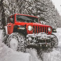 a red jeep is driving through the snow