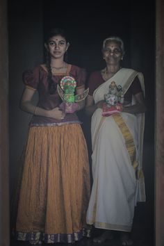 two women standing next to each other holding vases