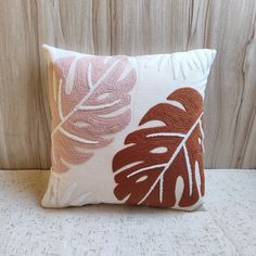 a white and brown pillow sitting on top of a wooden table next to a wall