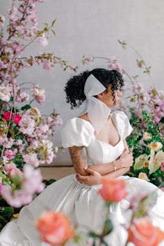 a woman in a white dress sitting next to flowers