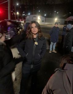 a woman standing in the middle of a street at night with her hands on her hips