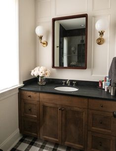 a bathroom with a checkered floor and black counter top, two mirrors above the sink