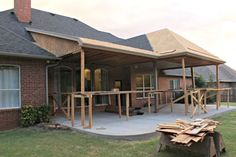 a house that is being built with wood on the front porch and covered in shingles