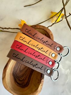 four leather bracelets with words on them sitting on top of a piece of wood