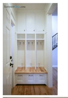 an empty room with white cabinets and wood flooring on the wall, and a wooden bench in front of it