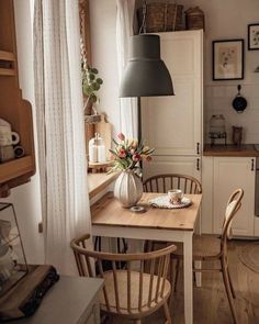 a kitchen table with two chairs and a vase filled with flowers sitting on top of it