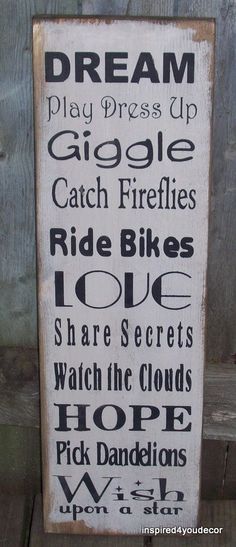 a wooden sign that says dream play dress up, go to the fireflies, ride bikes, love share secrets, watch the clouds, hope pick dandelions