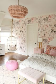 a bedroom with floral wallpaper and pink accessories on the bed, hanging from a chandelier