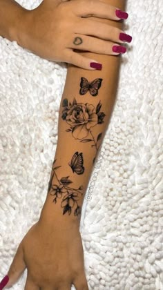 a woman's arm with flowers and butterflies tattooed on the left side of her hand