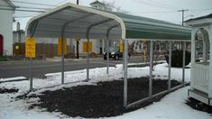 a covered bus stop sitting on the side of a road next to a white building