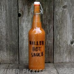 a bottle with writing on it sitting in front of a wooden fence that says killer not sauce