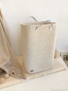 a large white basket sitting on top of a wooden table next to a towel rack