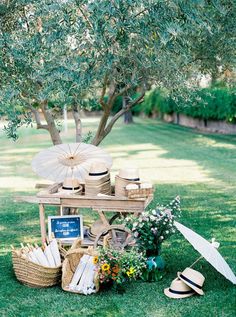 an umbrella and hat stand in the grass under a tree with other items on it