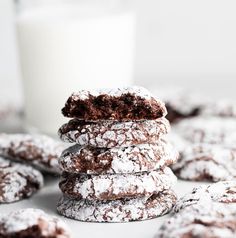 chocolate crinkle cookies stacked on top of each other next to a glass of milk