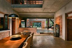 a dining room table and chairs in front of an open floor plan with brick walls