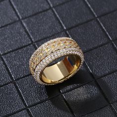 a gold ring with two rows of white and yellow diamonds in it on a black surface