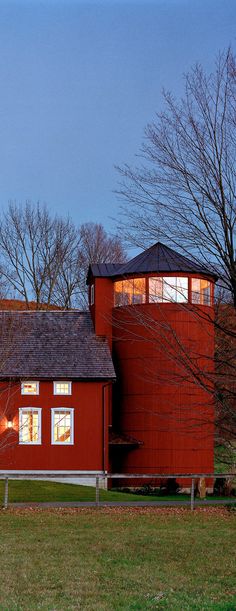 a red barn sits in the middle of a field with trees and grass around it