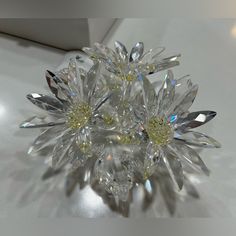 a close up view of a crystal flower on a white table top with other items in the background