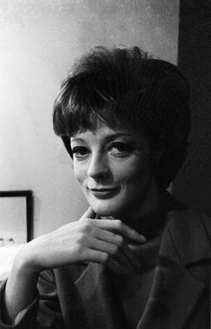 a black and white photo of a woman with her hand on her chin smiling at the camera