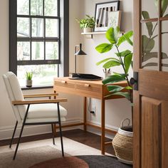 a room with a desk, chair and potted plant on the window sill